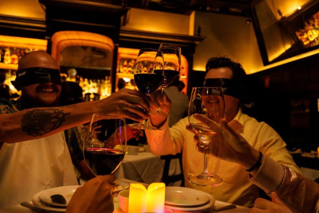 Several guests raise their glasses whilst blindfolded.