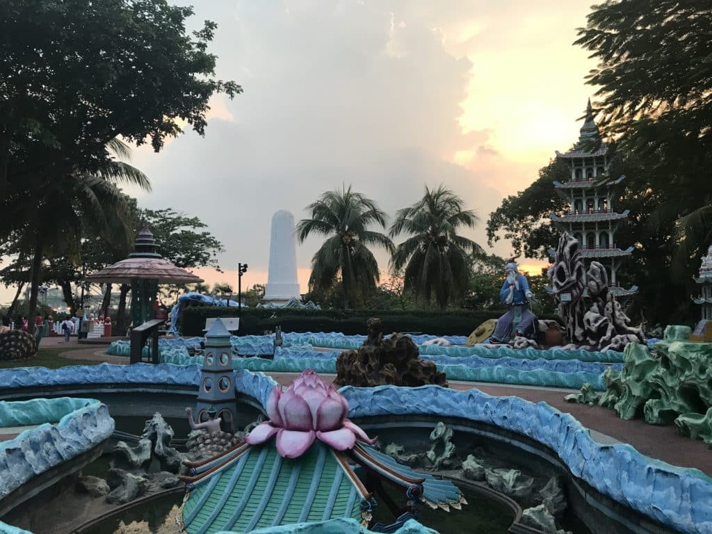 landscape at hell's museum in singapore showing flower sculptues, blue paths and tress in the background
