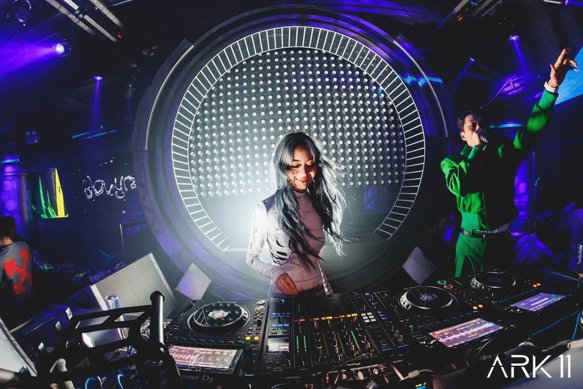 A female DJ smiles as she adjusts the decks at ARK11 Singapore.