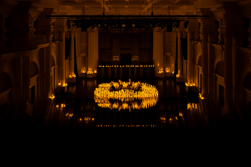 A wide shot of a string quartet performing on the stage at Victoria Concert Hall surrounded by hundreds of candles.
