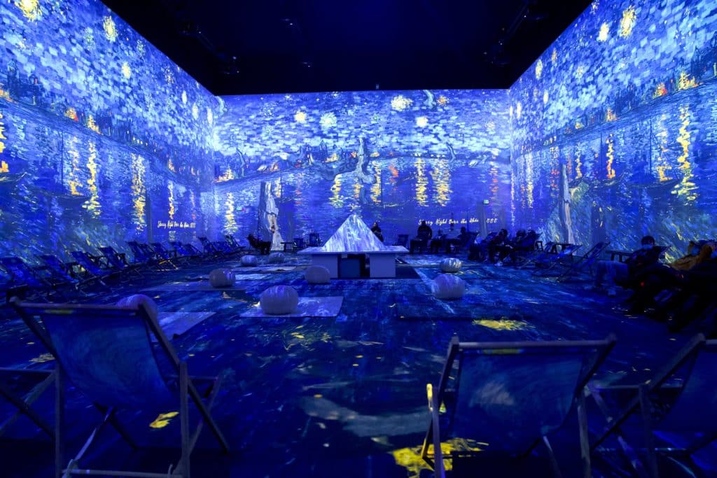 the immersive room at van gogh: the immersive experience showcasing the starry night in 360 degree with people seated within the four walls