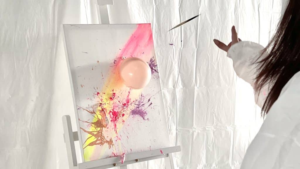 person throwing dart at paint-filled balloon at art pop studio in singapore