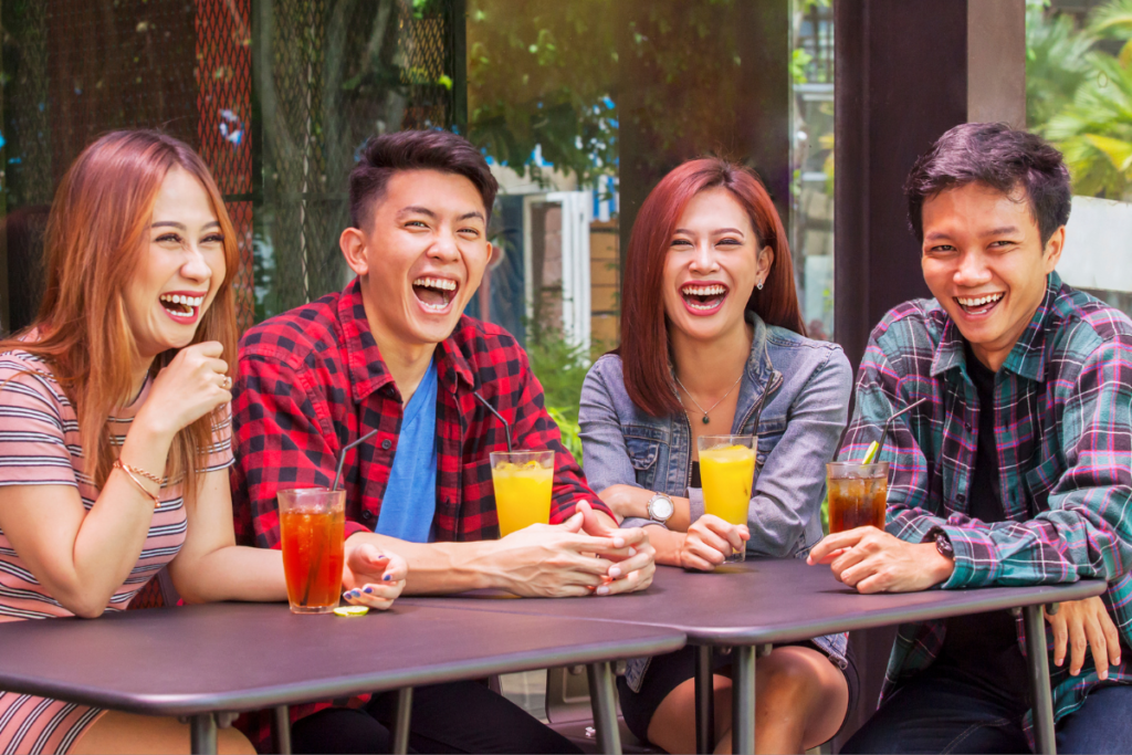 Four friends sitting at a table with drinks laughing