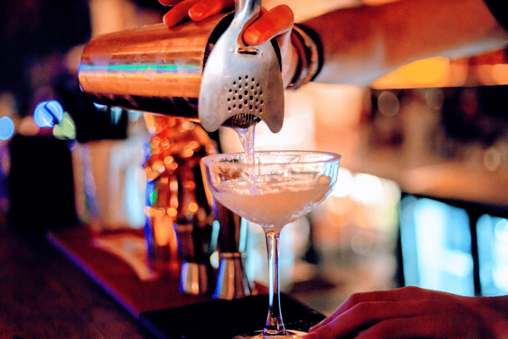 Cocktail glass being filled on a bar