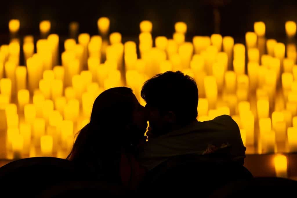 The silhouette of two people kissing with candles in the background
