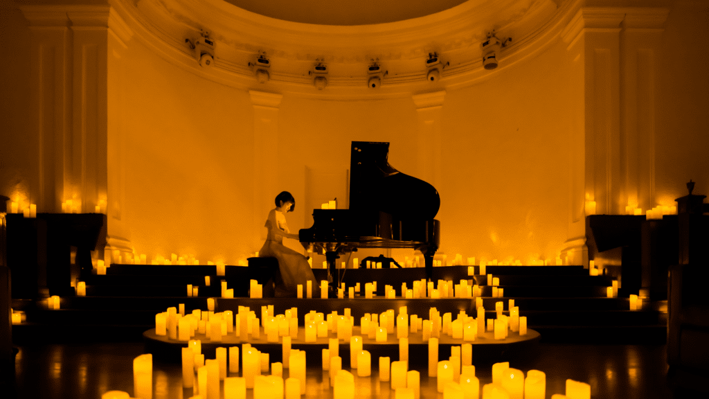 A woman playing the piano surrounded by hundreds of candles for a Candlelight concert.