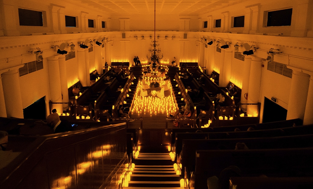 The vast interior of The Chamber at The Arts House In Singapore lit with hundreds of candles.